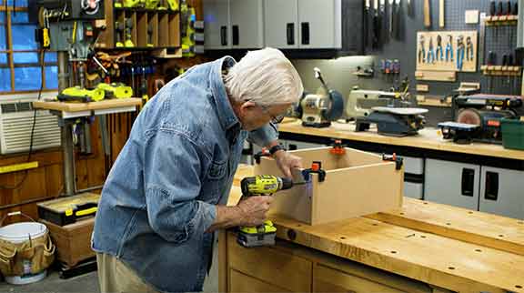 Man drills into a wooden box